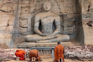 Moines priants devant une statut de Bouddha