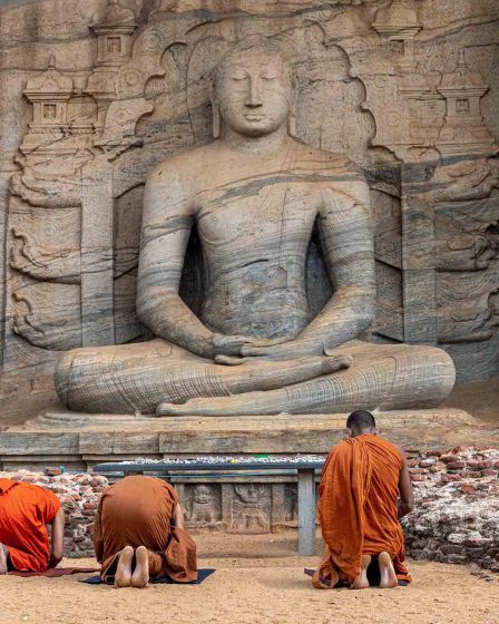 Moines priants devant une statut de Bouddha